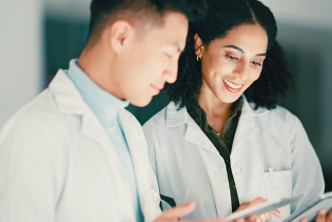 Two clinical researchers reviewing trial data on a tablet during multiple myeloma clinical trial planning.